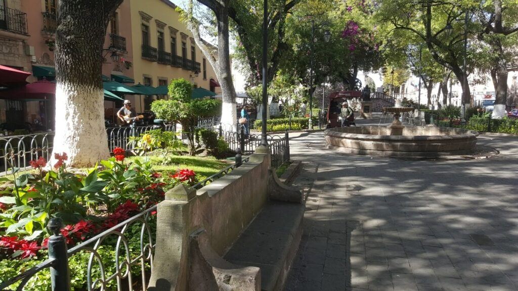 A plaza with garden, a fountain, and restaurants.