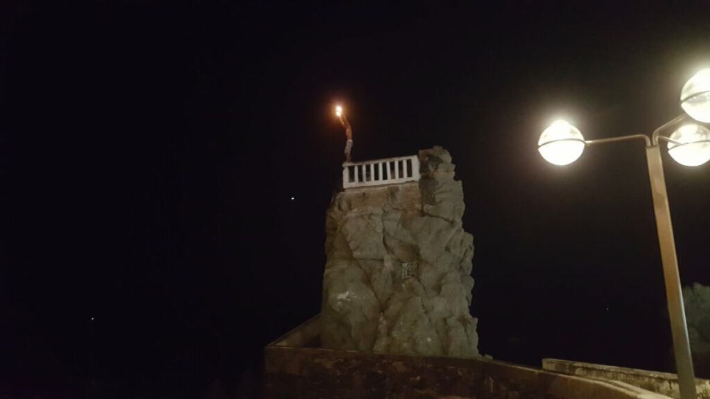 Cliff diver holding a torch in his hand.