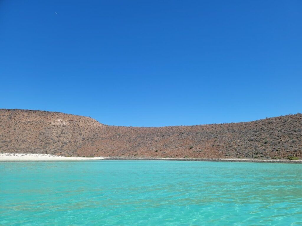 Turquoise water surrounding an island with hills.