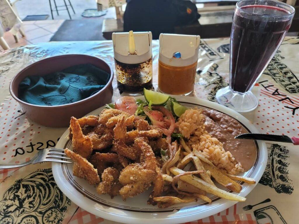 Fried shrimp with fries, beans, rice, and veggies.